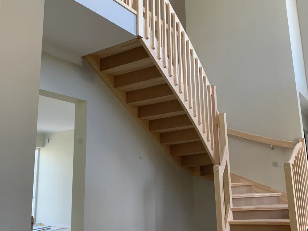Nybyggd trätrappa med räcke i ett trapphus